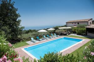 una piscina en un patio con sillas y sombrillas en Seacily Etna House, en Piedimonte Etneo