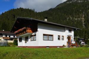 una casa blanca frente a una montaña en Ferienwohnung Frauenschuh, en Vorderhornbach