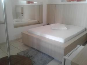a small bedroom with a bed and a mirror at Prime Motel in Criciúma