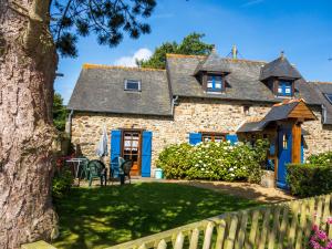 a stone house with blue doors and a tree at Maison de la Ferme in Lézardrieux