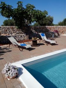 a swimming pool with two lounge chairs and a table at Agriturismo Masseria Alberotanza in Conversano
