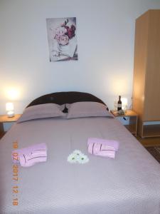 een bed met twee roze handdoeken en twee bloemen erop bij Sobe Žalac in Karlovac