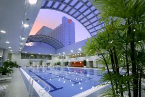 a swimming pool in a hotel with a glass ceiling at Sheraton Miyako Hotel Osaka in Osaka