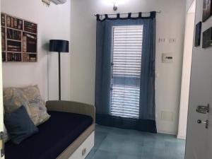 ポッツァッロにあるLa Casa del Pescatoreの青いカーテンとソファ付きの窓が備わる客室です。