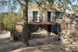 uma casa de pedra com uma mesa e uma árvore em Villa Les Carlets em Saignon