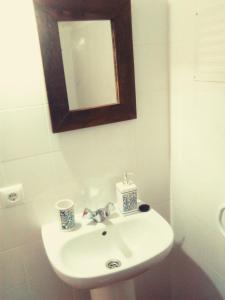 a bathroom with a white sink and a mirror at Palheiros da Ribeira in Pracana Cimeira