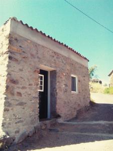 a small stone building with a door on the side at Palheiros da Ribeira in Pracana Cimeira