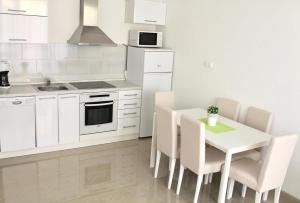 a kitchen with white cabinets and a table and chairs at Apartments Villa Milna 1 in Budva