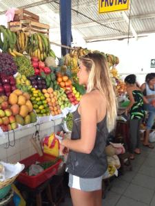 a woman standing in front of a fruit market at Blue Shark Apartments in San Bartolo