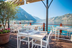 a row of tables and chairs on a deck next to the water at Hotel Casa del Mare - Amfora in Kotor