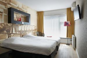 a hotel room with a bed and a flat screen tv at Stads Hotel Boerland in Emmen