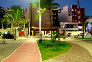 a walkway with palm trees in a city at night at Rede Andrade Mar Hotel - Rio Vermelho in Salvador