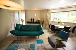 a living room with a green couch and chairs at Xenith Gastenverblijf in Apeldoorn