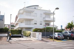 un edificio blanco con coches estacionados frente a él en Residence Speranza, en Lido di Jesolo