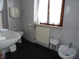 a white bathroom with a sink and a toilet at Hotel Florida in Molveno +29 photos