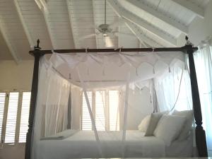 a bedroom with a canopy bed with white curtains at Aloe Villa in Five Islands Village
