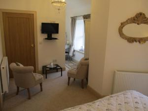 a bedroom with a bed and two chairs and a television at White Lodge B & B in Strathpeffer