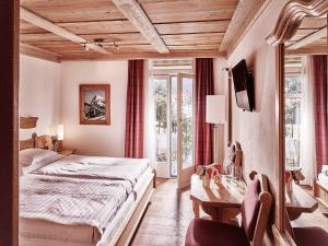 a bedroom with a bed and a desk and windows at Hotel Schönegg in Wengen