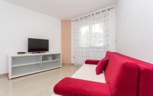 a living room with a red couch and a television at Apartment Kricin in Baška
