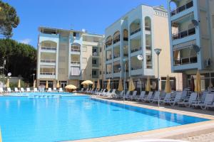 a swimming pool with chairs and umbrellas in front of buildings at Golem Apartments in Golem