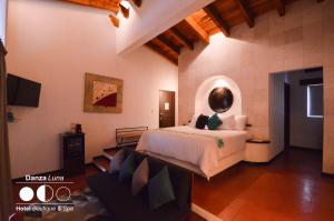 a bedroom with a bed and a couch in a room at Danzaluna Hotel Boutique in Valle de Bravo