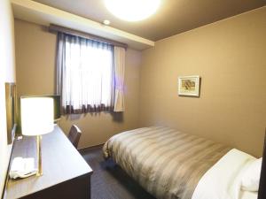 a hotel room with a bed and a window at Hotel Route-Inn Court Matsumoto Inter in Matsumoto