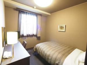 una camera d'albergo con letto e finestra di Hotel Route-Inn Court Matsumoto Inter a Matsumoto