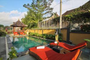 a swimming pool with two chairs and a gazebo at Surawan Bisma Ubud in Ubud