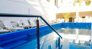 una piscina con sillas blancas junto a un edificio en Las Vegas Hotel Termal en Termas de Río Hondo