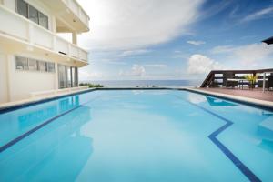 a swimming pool with the ocean in the background at Mai'I Villa Apartments in Rarotonga