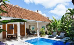 a villa with a swimming pool in front of a house at Villa Alliv in Seminyak