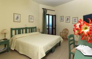 a bedroom with a bed and a table with a flower at Hotel Le Dune in Sabaudia