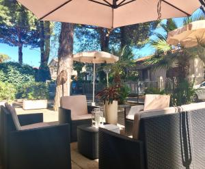a patio with tables and chairs and an umbrella at Alice Hotel in Cervia