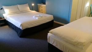 a hotel room with a bed and two nightstands at Blue Pacific Swansea in Swansea