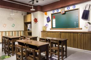 台北的住宿－富裕自由正義國小旅店 ，配有木桌和大屏幕的教室