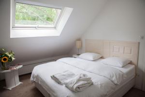 a bedroom with a bed with white sheets and a window at Cottage Markdal in Breda