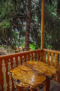 uma mesa de madeira numa varanda com uma árvore em EniRest em Karakol