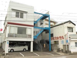 una furgoneta blanca estacionada frente a un edificio en Business Hotel Minshuku Minato en Tokushima