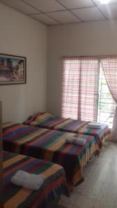 a bedroom with two beds and two windows at Hostal Doña Marta in San Salvador
