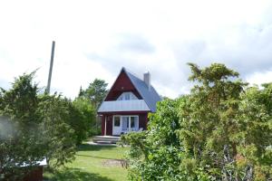 a red and white house with trees in front of it at Tinore Holiday Home in Muratsi +4 photos
