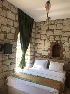 a bedroom with a bed in a stone wall at Kerme Ottoman Alacati in Alaçatı