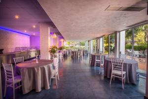 a dining room with tables and chairs and windows at Hotel Apollo in Mamaia