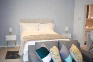 a bedroom with a bed with a couch and pillows at Tower Bliss Apartment in Gaborone