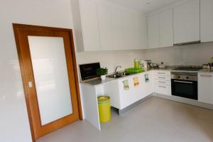 una pequeña cocina con armarios blancos y puerta en Secret Guest House, en Gafanha da Vagueira