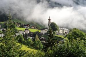a village with a church in the middle of a mountain at Alpakahof Strieder in Maria Luggau