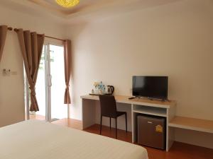 a bedroom with a desk with a television and a bed at Nice Sea Resort in Srithanu