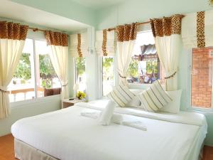 a bedroom with two large white beds with windows at Nice Sea Resort in Srithanu