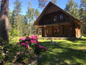 a log cabin in the woods with purple flowers at Meresihi talu in Vainupea