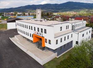 ヴォルフスベルクにあるAIS Centerのオレンジ色のアクセントが特徴の白い大きな建物の空中風
