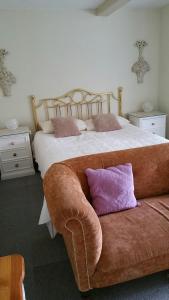 a bedroom with a bed and a couch with a purple pillow at Great Danes Country Inn in Swaffham